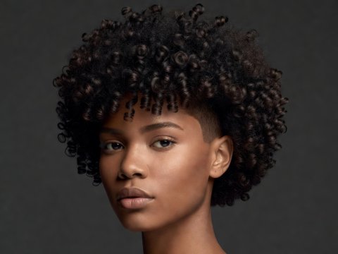 Three-quarter view of a sculpted 4B coily halo haircut with tapered sides and full rounded crown silhouette